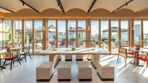 A modern dining area with a large table, multiple chairs, and a view of the cityscape through large windows. - Kew Green Chengdu  Hotel (Chengdu)