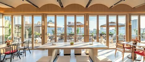 Un comedor moderno con una mesa grande, varias sillas y vistas de la ciudad a través de amplios ventanales.