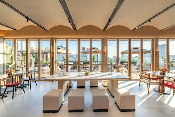A modern dining area with a large table, multiple chairs, and a view of the cityscape through large windows. - Kew Green Chengdu Hotel (Chengdu)