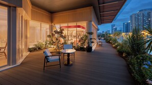 A modern outdoor area with a wooden deck, seating, and a glass facade building. - Kew Green Chengdu  Hotel (Chengdu)