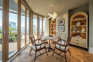 Ein Essbereich mit einem runden Tisch, vier Stühlen und Blick durch große Fenster auf einen Außenbalkon.