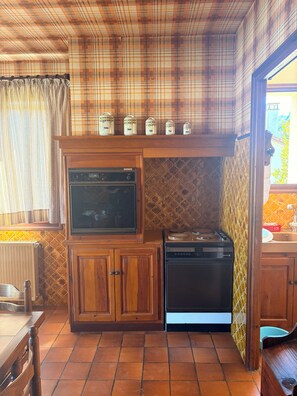 A kitchen with wooden cabinets, a built-in oven, and a stove.