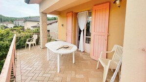 Uma varanda com mesa e cadeiras, uma porta rosa e vista da região ao redor.
