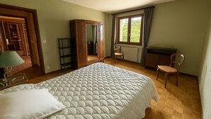 Quarto com cama, cadeira, escrivaninha, guarda-roupa e janela com cortinas.