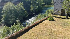 Uma ponte de pedra sobre um rio, rodeada por vegetação e edifícios.