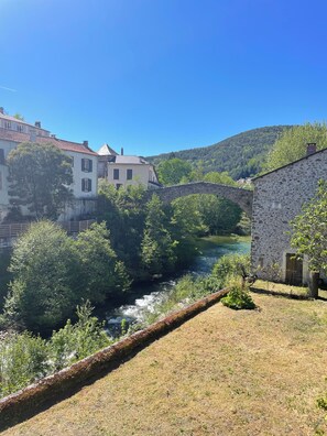 A stone bridge over a river, surrounded by greenery and buildings. - Family home with a garden and a patio (Saint-jean-du-bruel (12230))