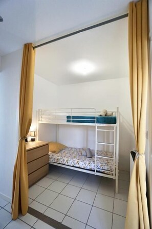 A bunk bed room with curtains, a dresser, and a lamp. - Swimming pool with a 100-meter cable winch, located 100 meters from the beach* (Guidel)