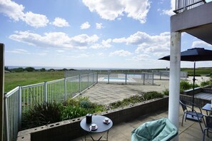 An outdoor patio area with a pool, surrounded by a metal fence, and a view of the landscape. - Swimming pool with a 100-meter cable winch, located 100 meters from the beach* (Guidel)