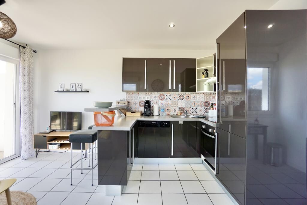 A modern kitchen with a central island, built-in appliances, and a large window.