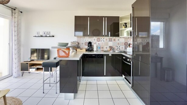 A modern kitchen with a central island, built-in appliances, and a large window. - Swimming pool with a 100-meter cable winch, located 100 meters from the beach* (Guidel)