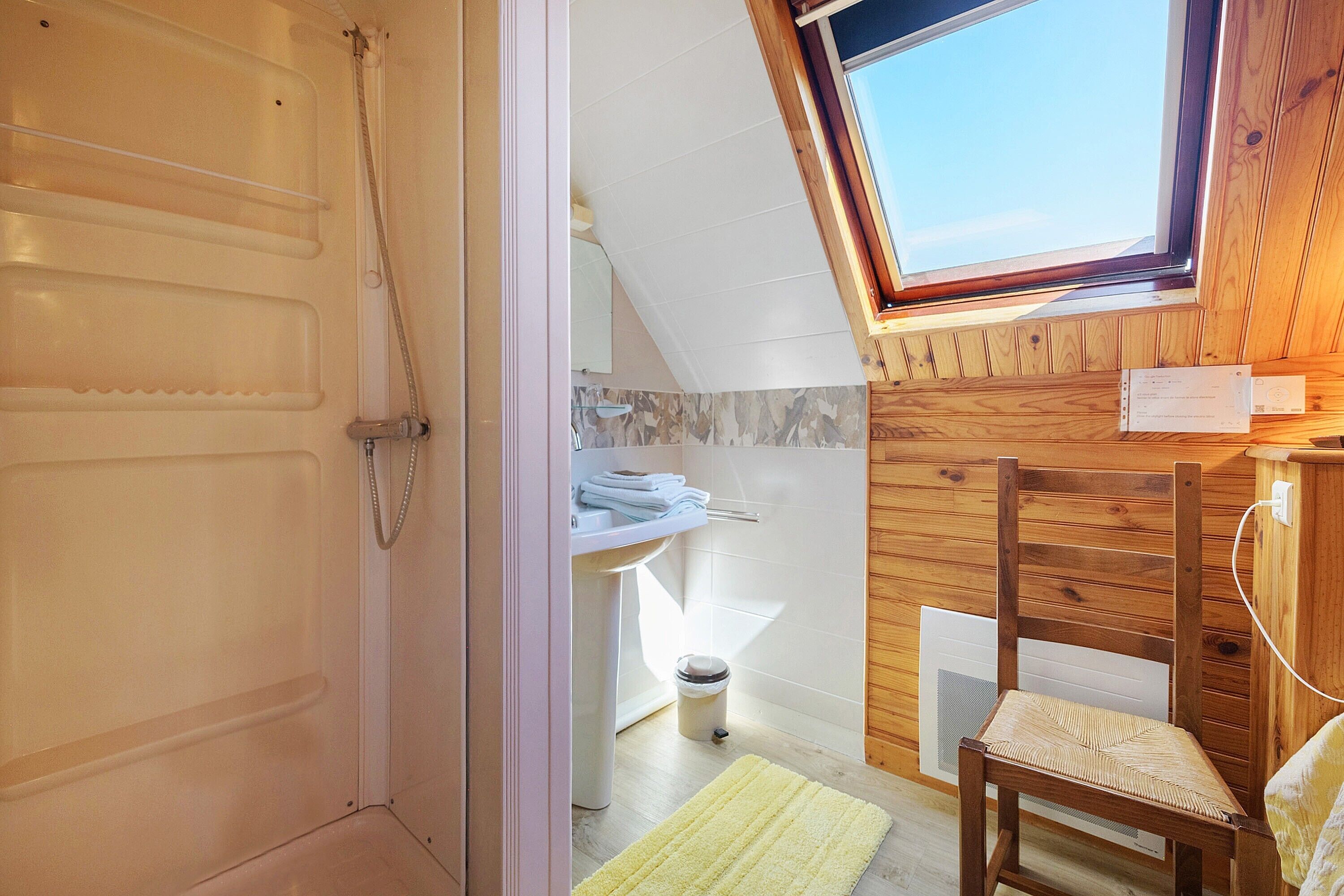 A bathroom with a shower, a sink, and a window.