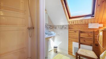 A bathroom with a shower, a sink, and a window.