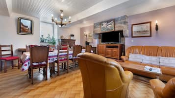 Una sala de estar con sofá, sillas, una mesa de comedor con sillas, televisor y chimenea.