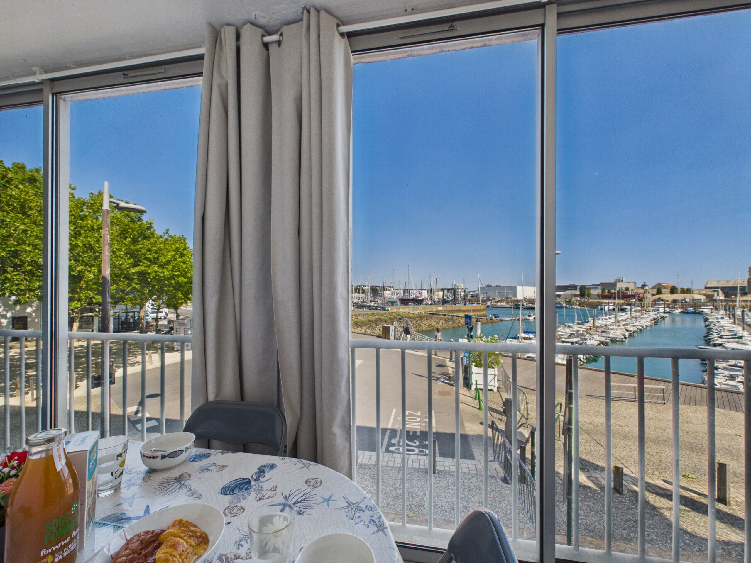 A balcony with a table set for dining, overlooking a marina with boats.