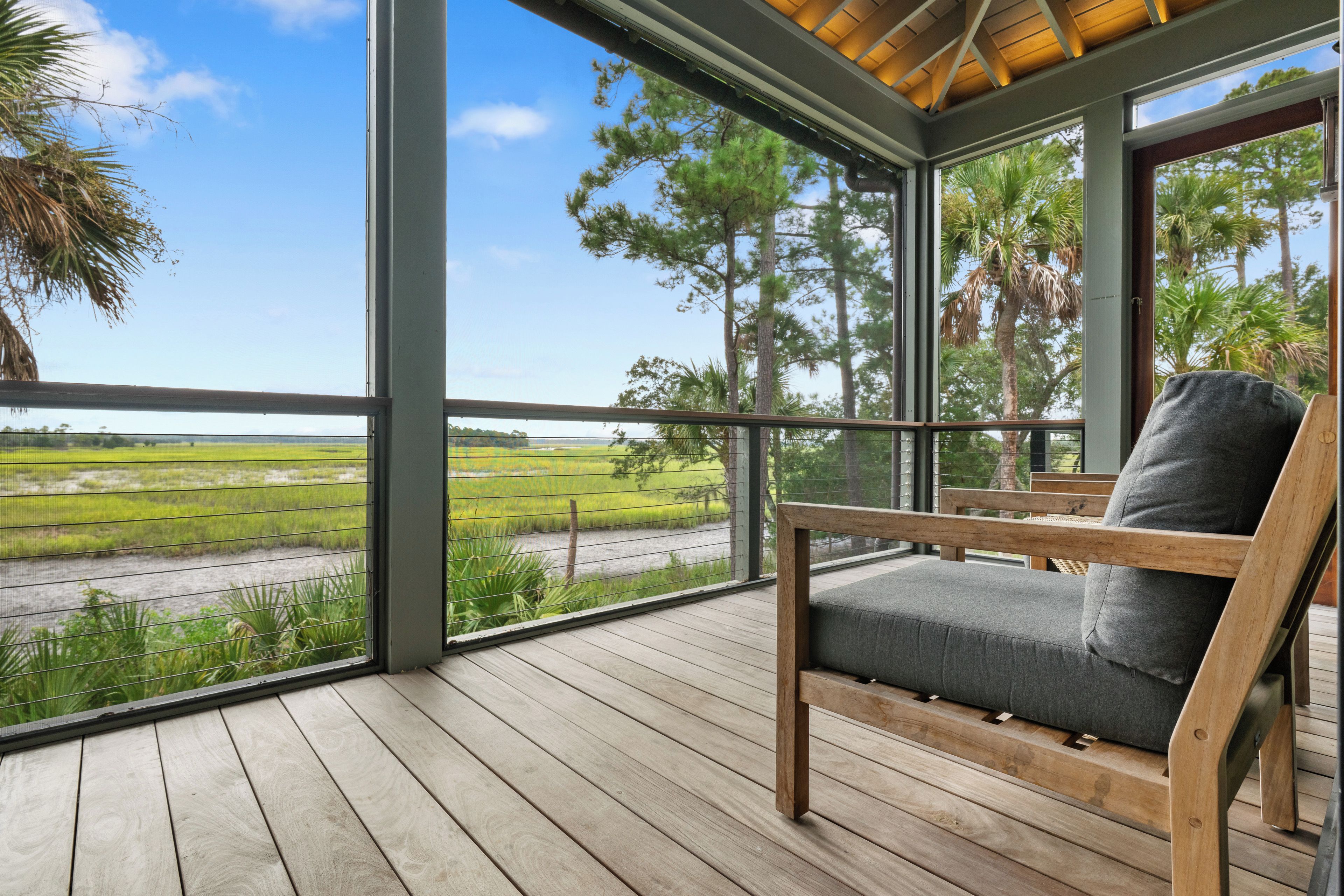 A wooden deck with a view of a green landscape and a clear sky.