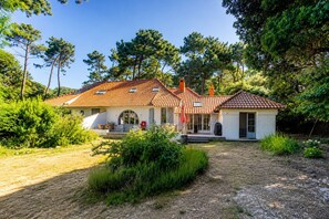 Ein zweistöckiges Haus mit Ziegeldach, einer Veranda und einer kleinen angebauten Garage.