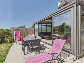 A modern outdoor patio with a glass enclosure, a dining table, chairs, and a seating area with a sofa and a TV. - House for 8 p, 400m from the beach, Kerlouan (Kerlouan)