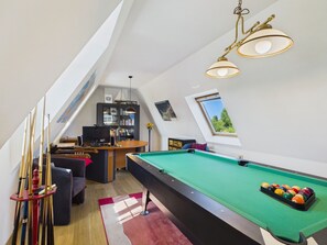 Ein Billardtisch mit grüner Spielvliesbahn, ein Poolstöckchenhalter und ein Billardkugelhhalter.