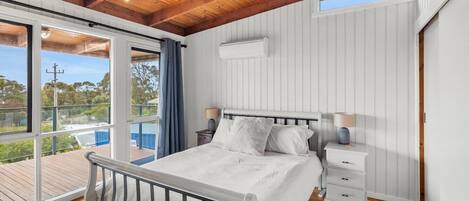 Un dormitorio con cama, mesitas de noche, una ventana y vistas al exterior.