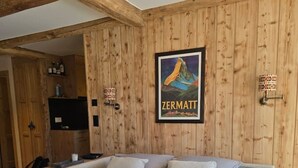 A bedroom with a bed, wooden walls, a poster, and a small table with items. - Cozy, Alpine • Terrace • Indoor parking (Val de Bagnes)