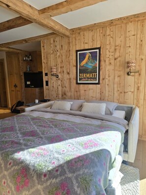A bedroom with a bed, wooden walls, a poster, and a small table with items. - Cozy, Alpine • Terrace • Indoor parking (Val de Bagnes)