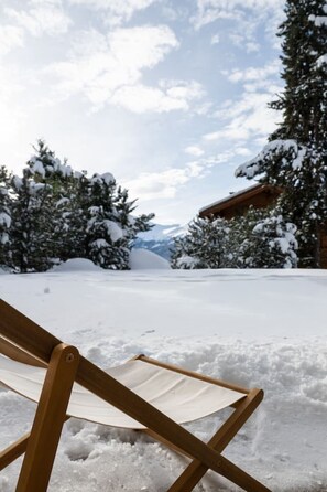 A wooden deck chair in a snowy landscape with a mountain in the background. - Cozy, Alpine • Terrace • Indoor parking (Val de Bagnes)
