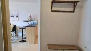 Een gang die uitkomt in een eetruimte met een bank en een plank.