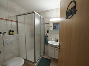 Kylpyhuone, jossa on suihku, wc, pesuallas ja peili.