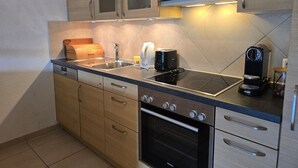 Een moderne keuken met houten kasten, een inbouwoven en een koffiezetapparaat.
