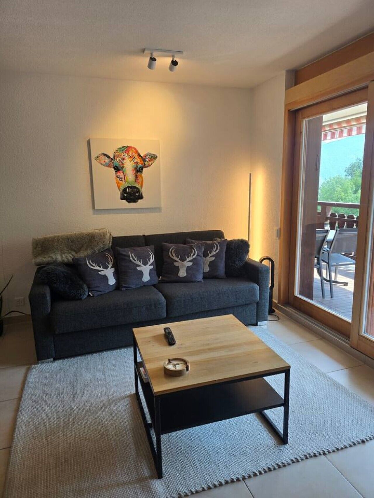 A living room with a sofa, a coffee table, and a painting of a cow.
