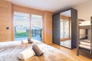 Un dormitorio con una cama grande, puerta corredera a un balcón y vistas a las montañas.