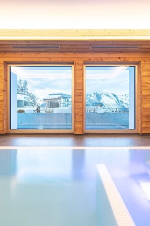 Ein Zimmer mit zwei großen Fenstern, das einen Blick auf eine verschneite Landschaft und ein Gebäude bietet.
