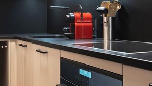 A modern kitchen with a black countertop, stainless steel appliances, and a red kettle. - Ski-in/Ski-out • Mountain View • Spa & Sauna (Nendaz)