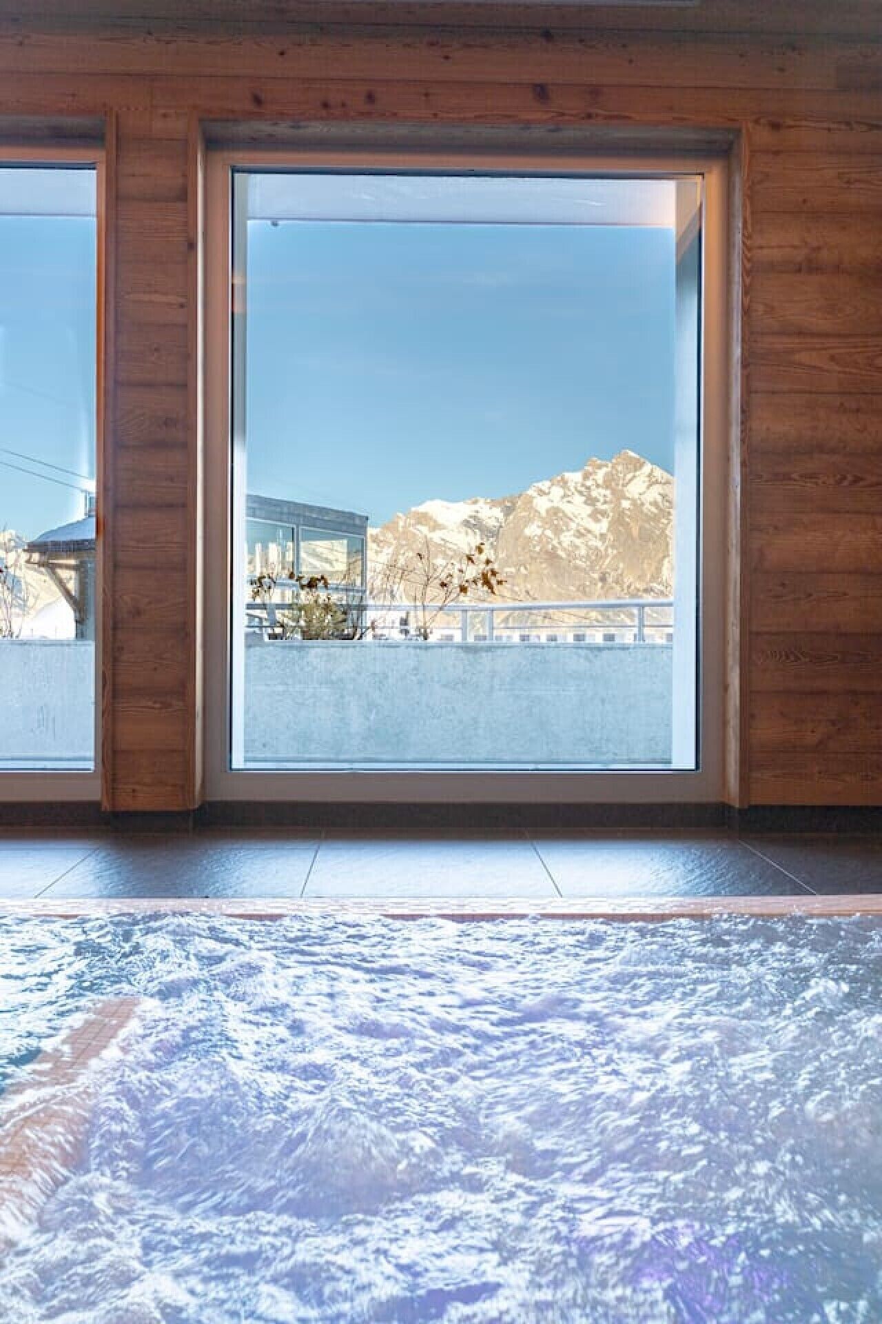 A room with large windows, wooden walls, and a view of a snowy mountain landscape.