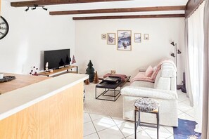 A living room with a sofa, a coffee table, a TV, and framed pictures on the wall. - Cozy & Bright • 1 Bedroom • Ovronnaz (Leytron)