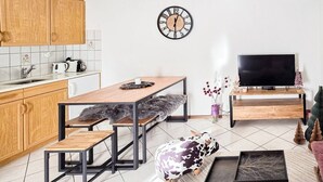 En kompakt bolig med tekøkken, spiseplads og et fjernsyn.