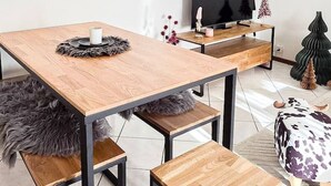 Et moderne spiseområde med et træbord, bænke og en ramme af sort metal.