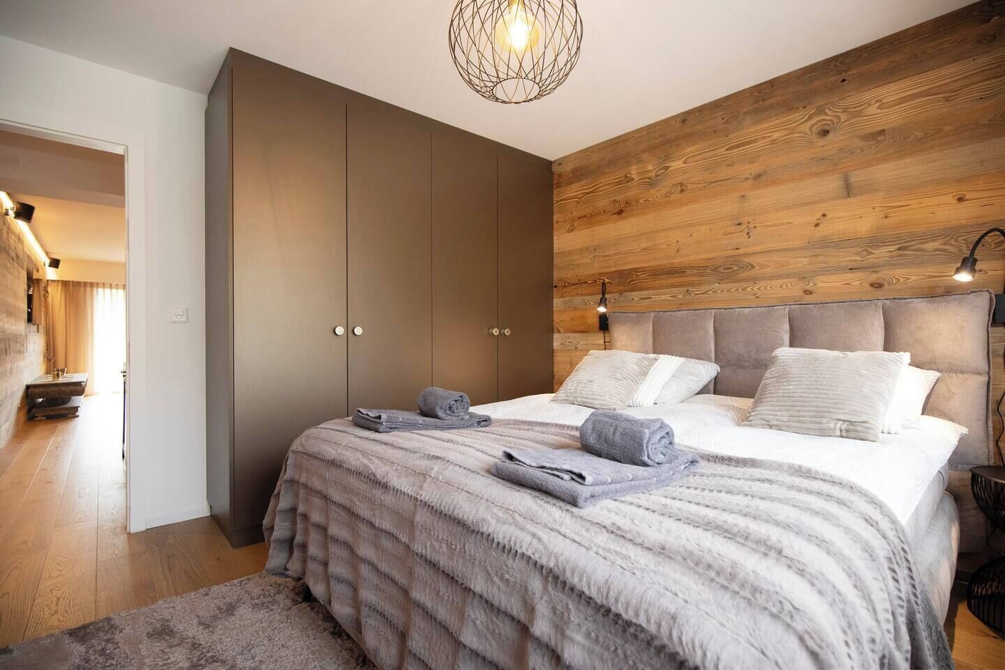 Une chambre avec un grand lit, une armoire et un mur en bois.