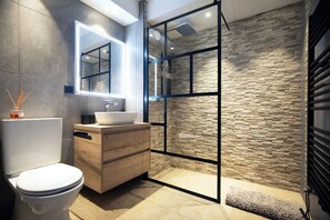 Een moderne badkamer met toilet, wastafel en een douchecabine met glazen wanden.