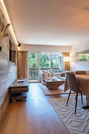 Ein modernes Wohnzimmer mit Holzboden, einer Couch, einem Couchtisch und einem Essbereich mit Stühlen.