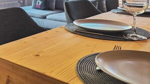 Een eetgedeelte met een houten tafel, een wijnglas en een bank met kussens.