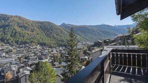 Een balkon met uitzicht op een stad, gelegen tegen een bergachtige achtergrond.