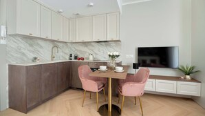 Una cocina moderna con encimeras de mármol, horno empotrado y comedor con sillas rosadas y mesa de madera.
