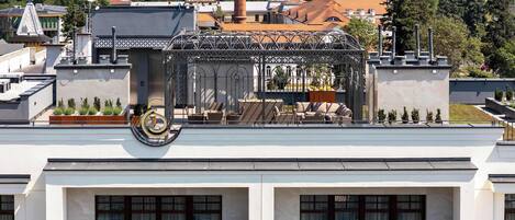 A building with a rooftop terrace, large windows, and a decorative metal structure.