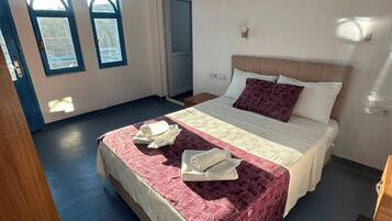 A hotel room with a bed, a window, and a door.