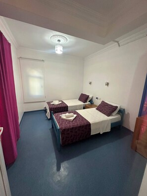 A room with two beds, a window, a ceiling fan, and a door. - PATARA BLUE HOTEL (Kas)