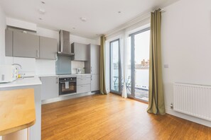 A modern kitchen with grey cabinets, a built-in oven, and a window with curtains. - Cozy 1BDR Flat with Fast WiFi near Heathrow (Greater London)