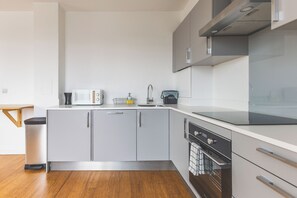 A modern kitchen with grey cabinets, a stainless steel dishwasher, and a black stove. - Cozy 1BDR Flat with Fast WiFi near Heathrow (Greater London)