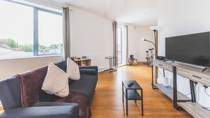 Ein modernes Wohnzimmer mit einer Couch, einem Couchtisch, einem Fernseher und einem Fahrrad im Hintergrund.