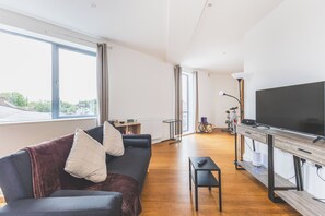 Ein modernes Wohnzimmer mit einer Couch, einem Couchtisch, einem Fernseher und einem Fahrrad im Hintergrund.